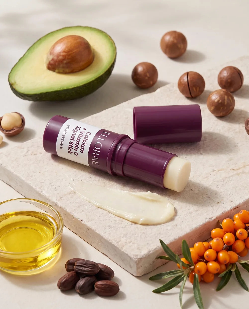 The open balm stick with a swatch of balm, avocado, jojoba, macadamia and sea buckthorn