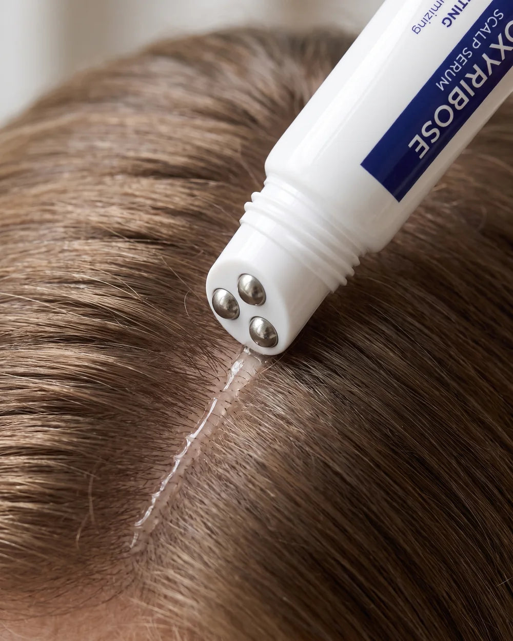 The three steel roller balls gliding serum along a part in dry hair