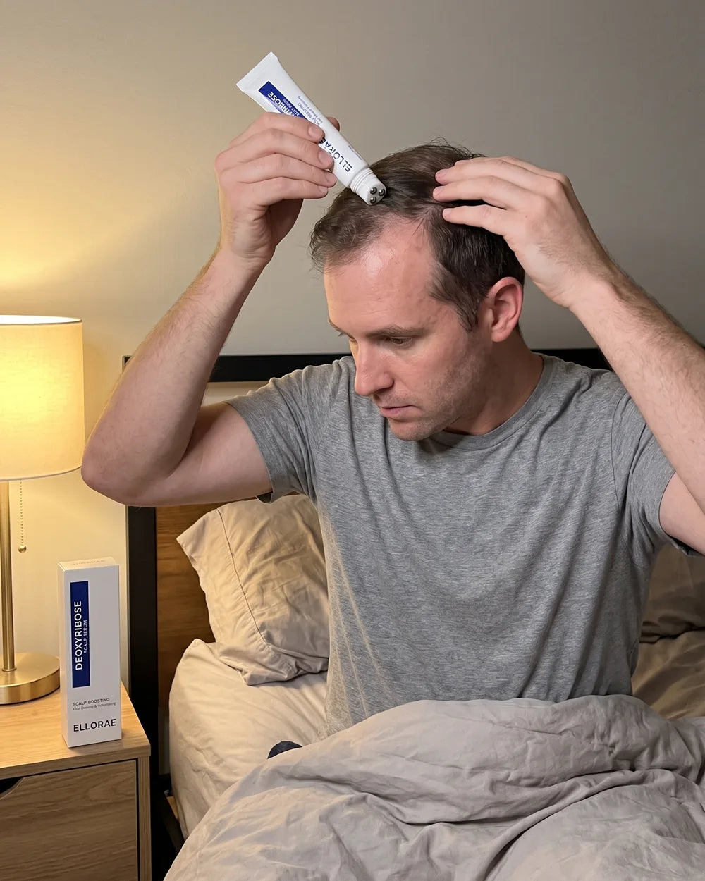 Man on the edge of his bed at night rolling the serum along his crown